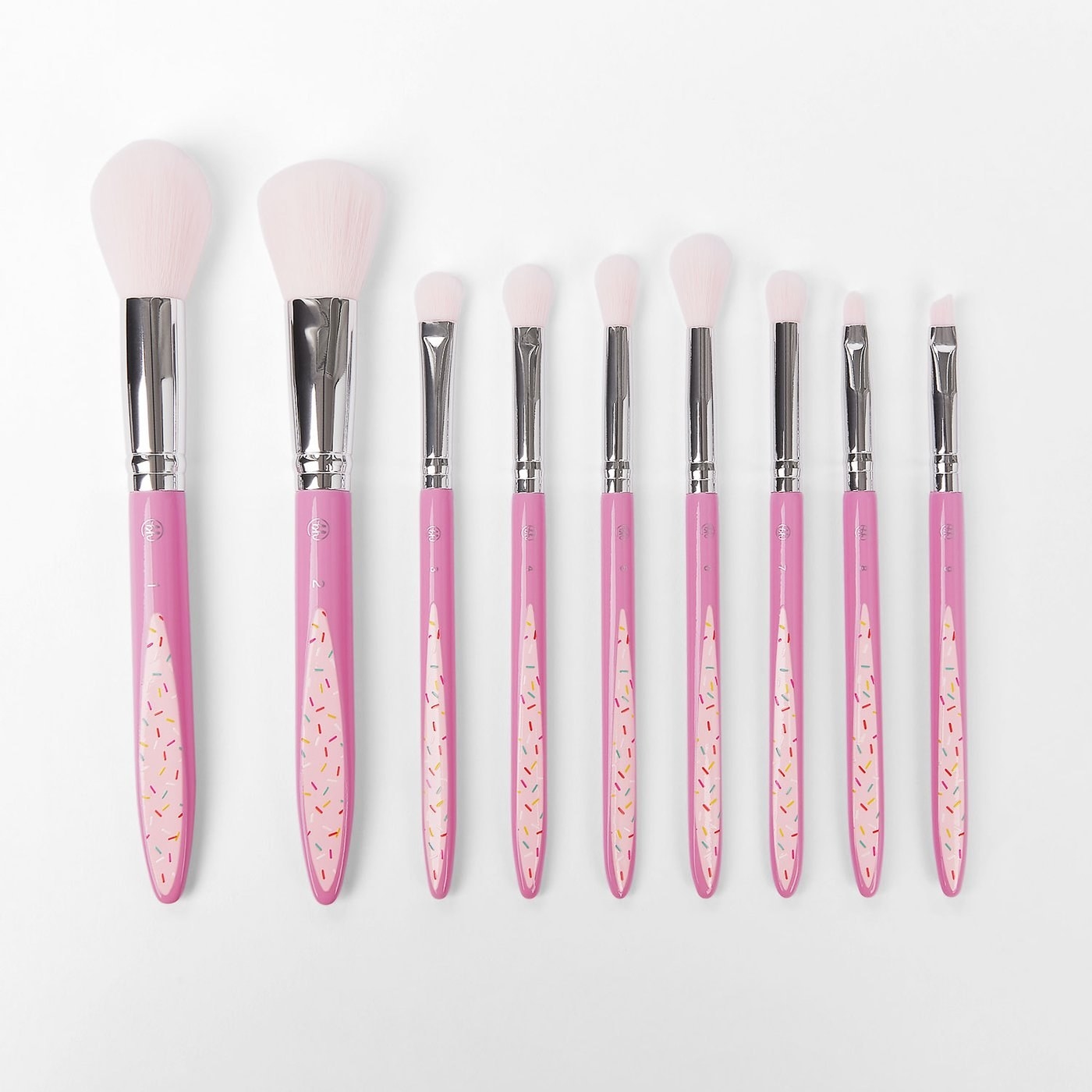 Nine pink-handed makeup brushes with a sprinkle print and white brush heads 