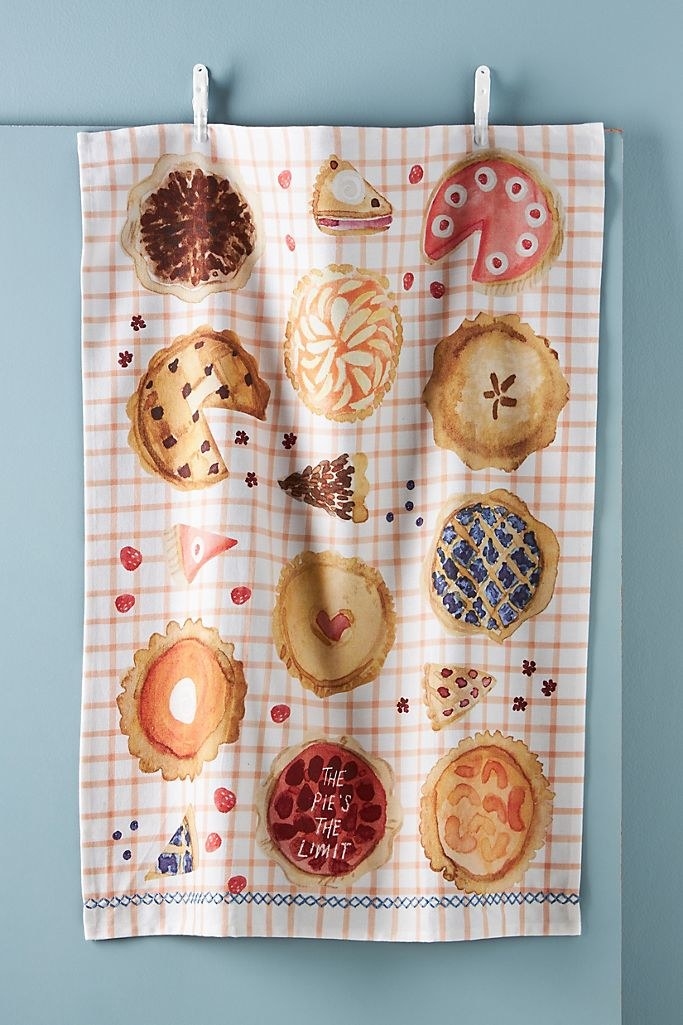 A checker print tea towel with water color pies on it including one that says &quot;the pie&#x27;s the limit&quot; 