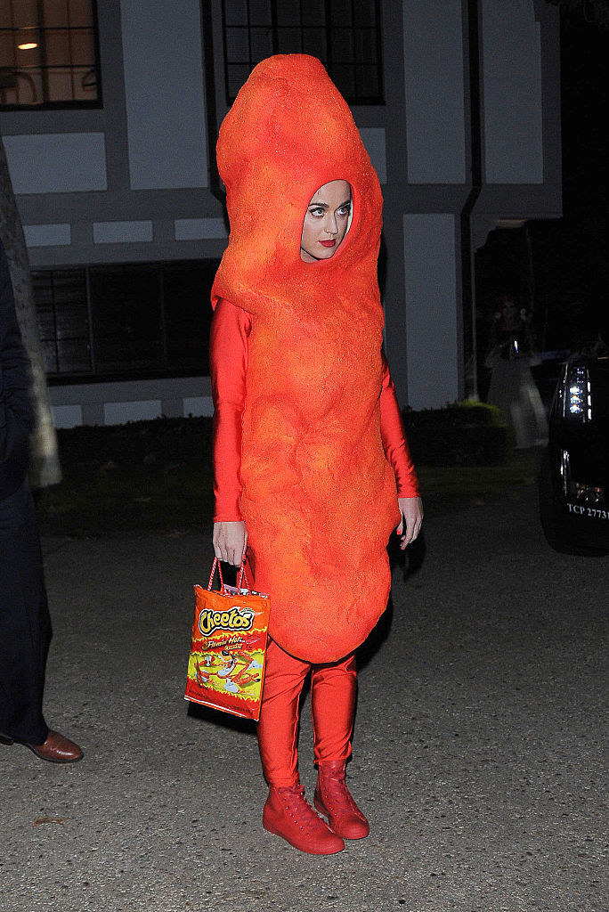 Katie Perry dressed as a Cheeto and holding a Cheeto bag purse for Halloween in 2014