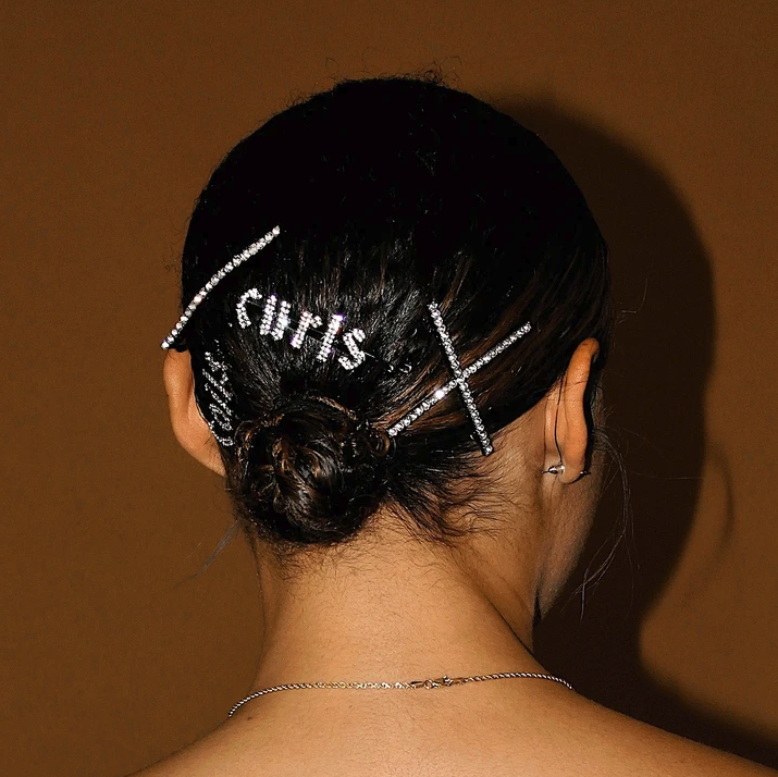 a rhinestone hair clip that says &quot;curls&quot; in a model&#x27;s hair 