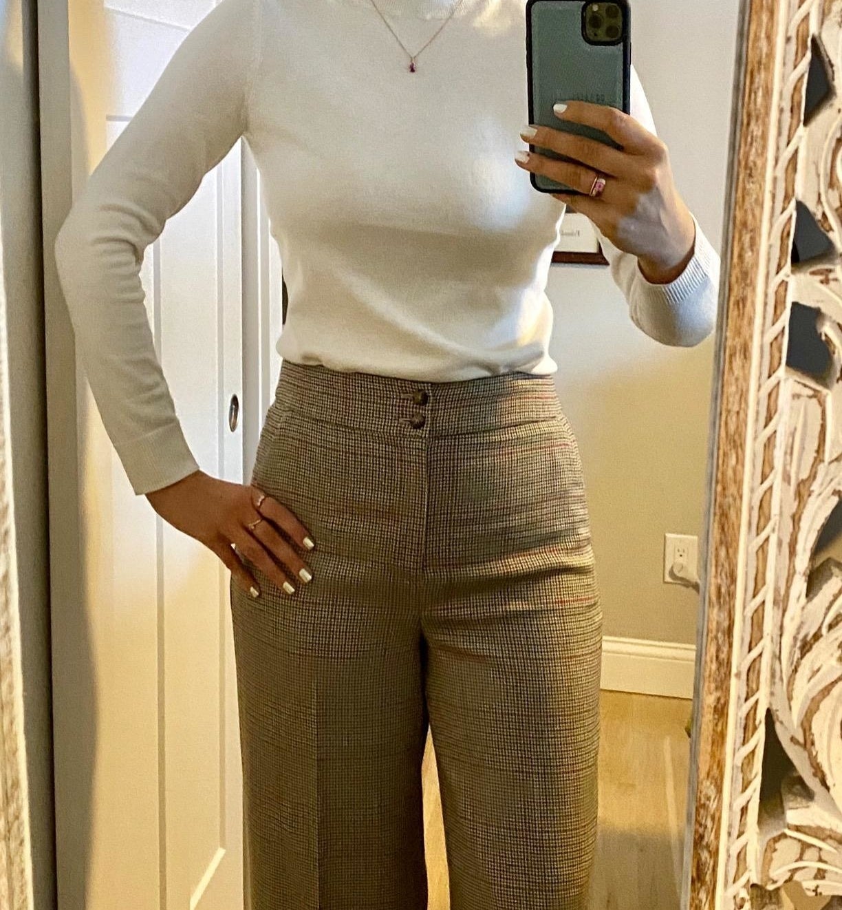 mirror selfie of a reviewer wearing a cream mock neck sweater tucked into brown pants