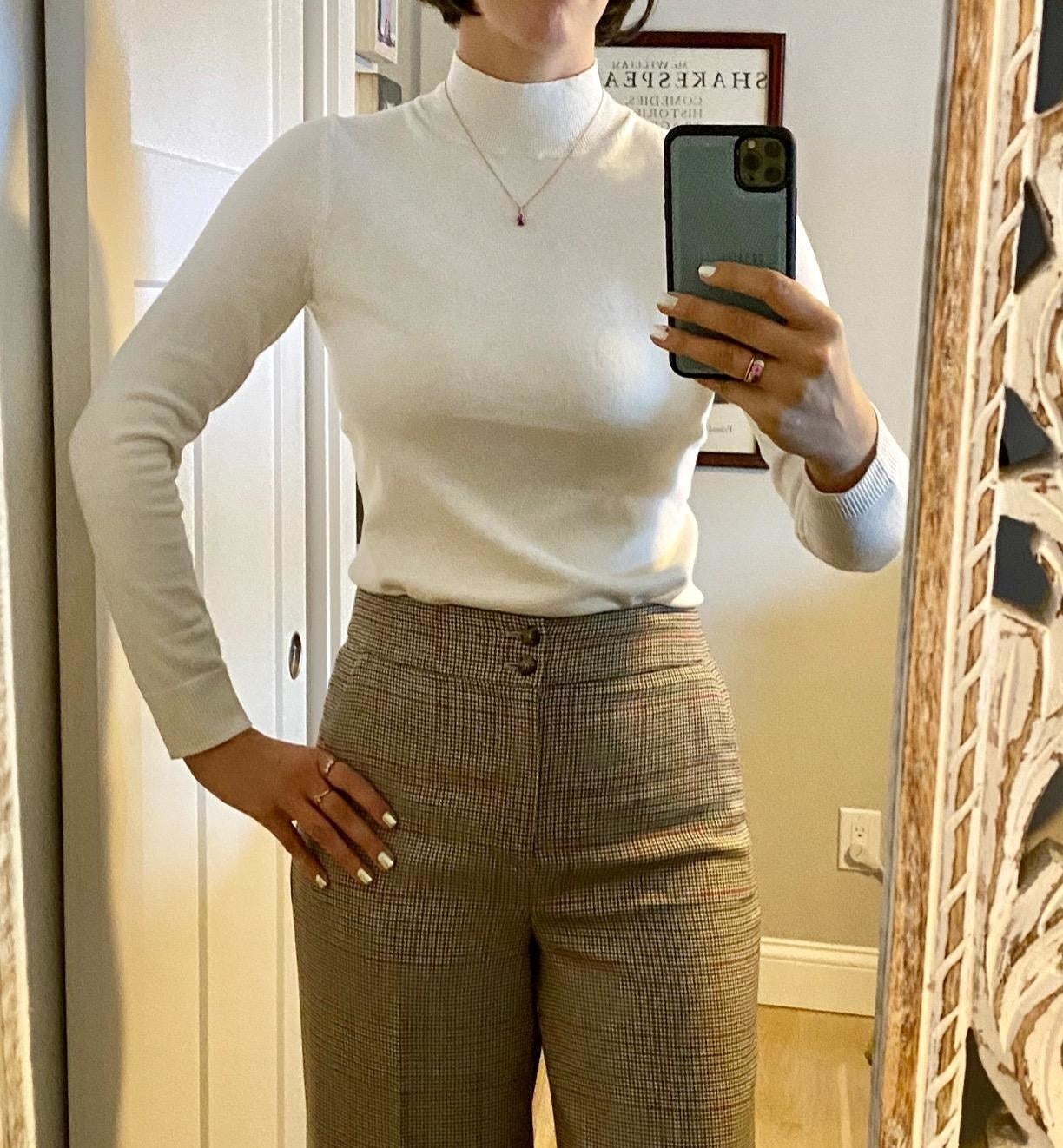 mirror selfie of a reviewer wearing a cream mock neck sweater tucked into brown pants
