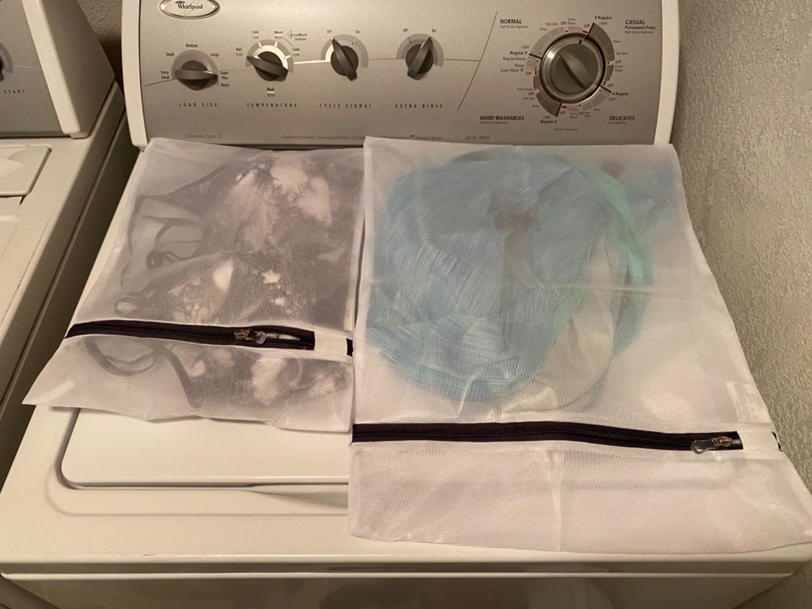 Reviewer photo of different size laundry bags with clothing in them on top of washing machine