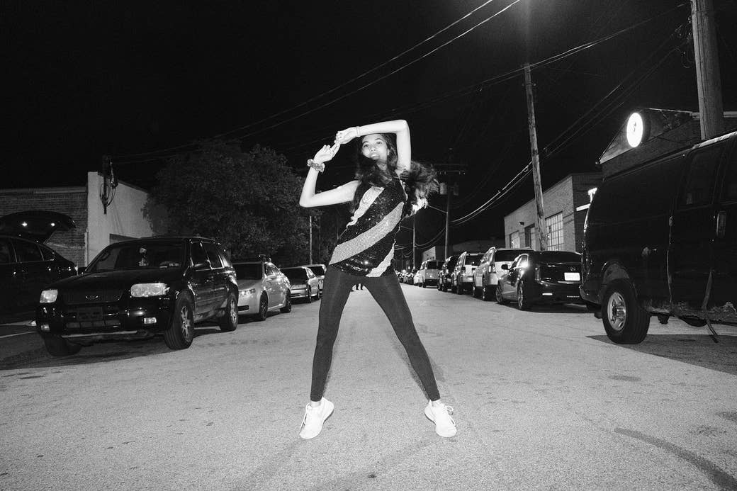 A black-and-white photo of a girl dancing in the street at night