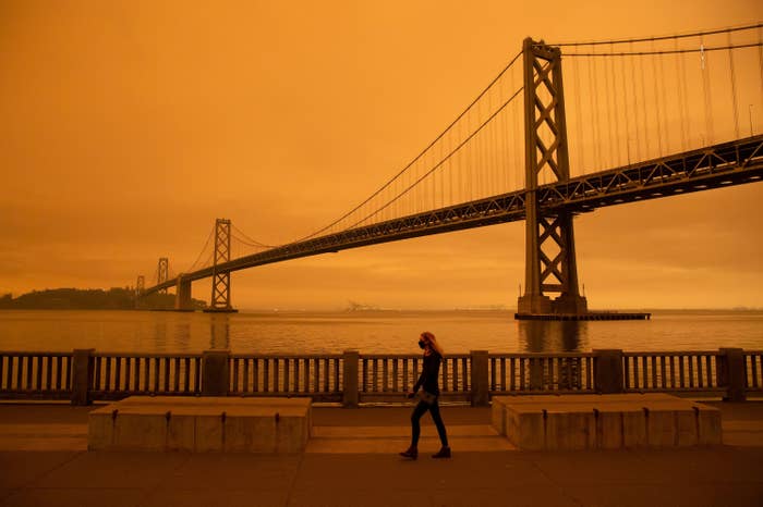 Woman wearing a mask walking past a bridge