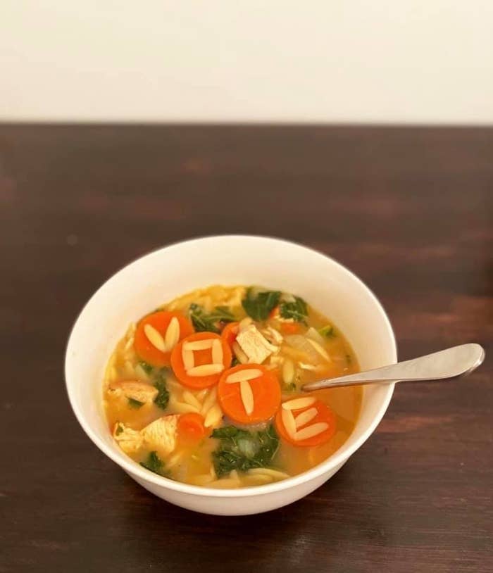 A bowl of chicken soup with &quot;vote&quot; spelled out in orzo pasta on top of sliced carrot rounds