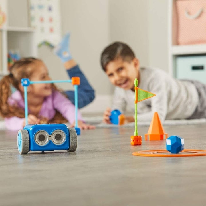 Two child models playing with wheeled blue robot
