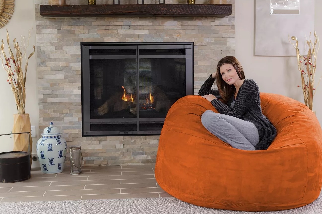 A bright orange bean bag with a woman sitting on top