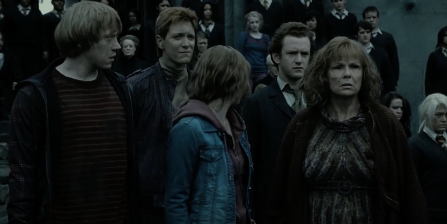 Percy standing with the Weasley family outside of Hogwarts