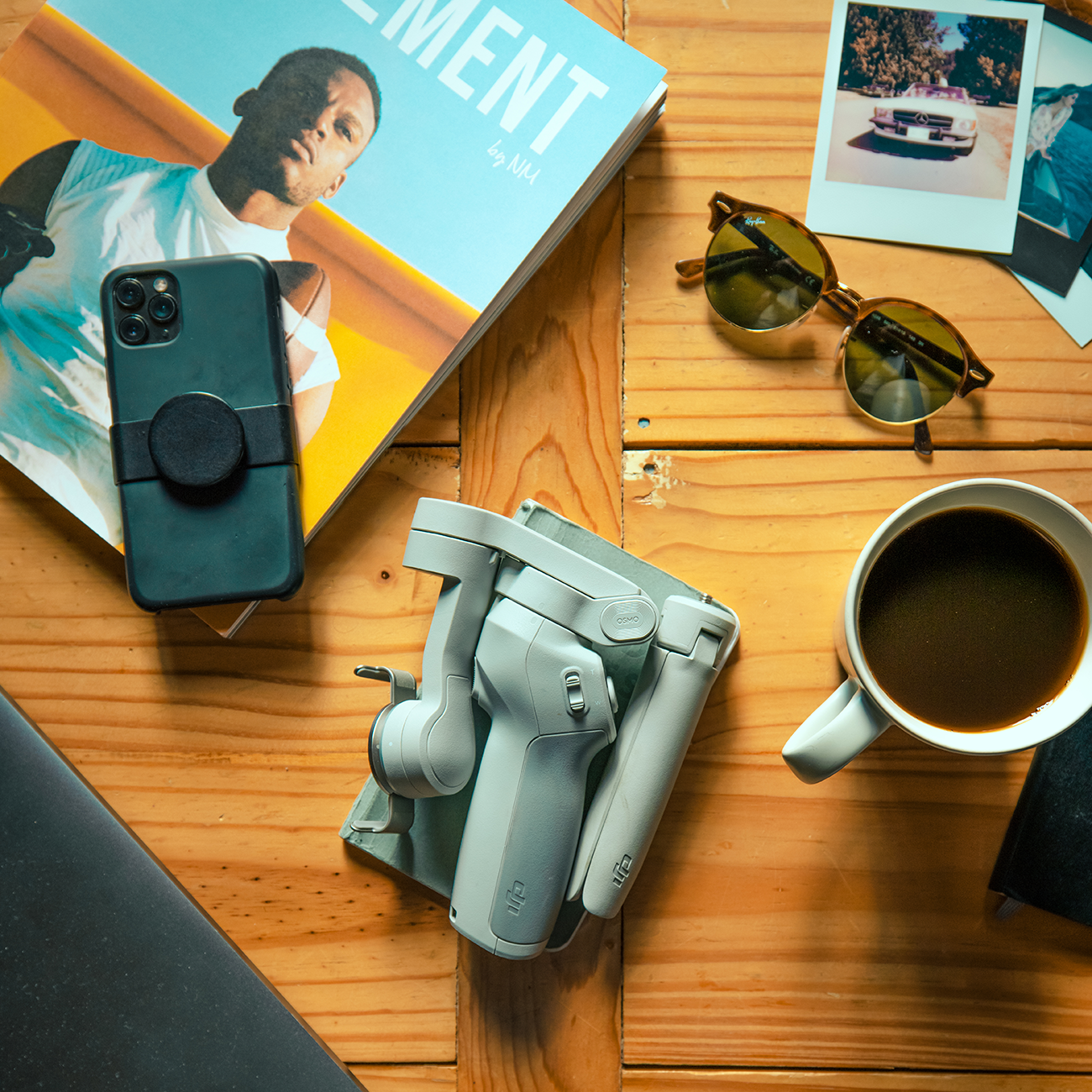 The DJI OM 4 on a table amongst a cup of coffee, a magazines, sunglasses and a phone
