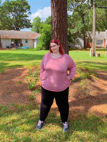 A different reviewer wearing the tee in pink with their hands in the pockets