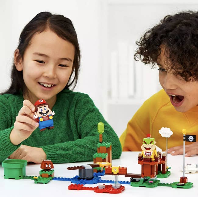 Two children playing with a Super Mario Lego set