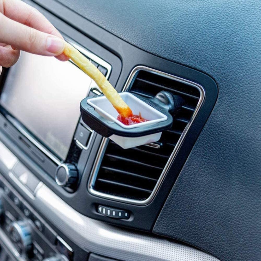 A bottle of dipping sauce attached to a car vent