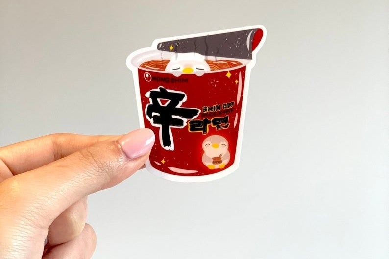 A person holding a sticker of ramen