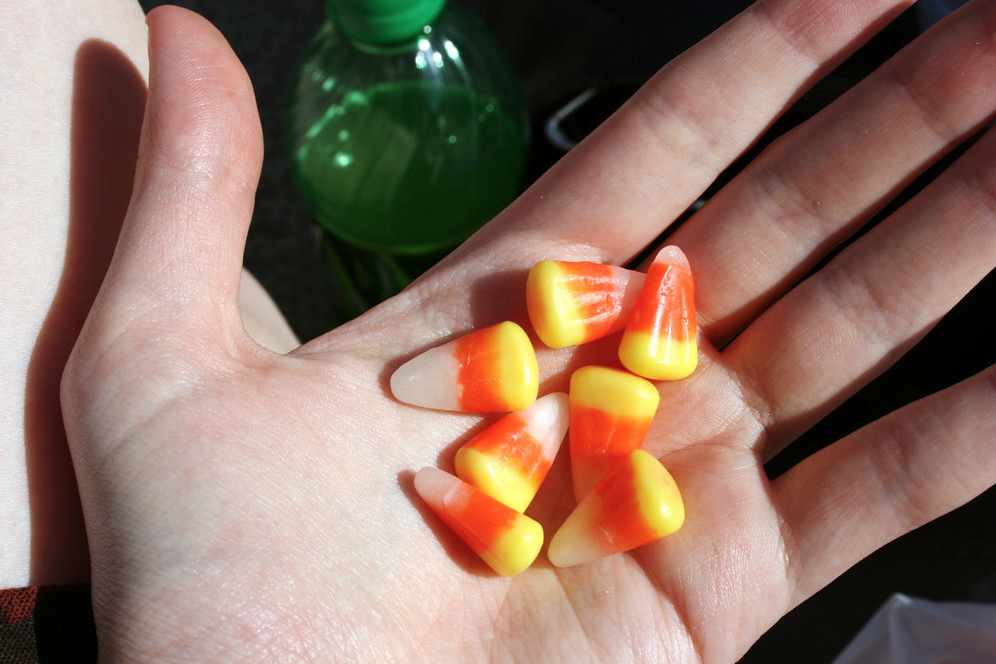 A hand holding a couple of pieces of candy corn