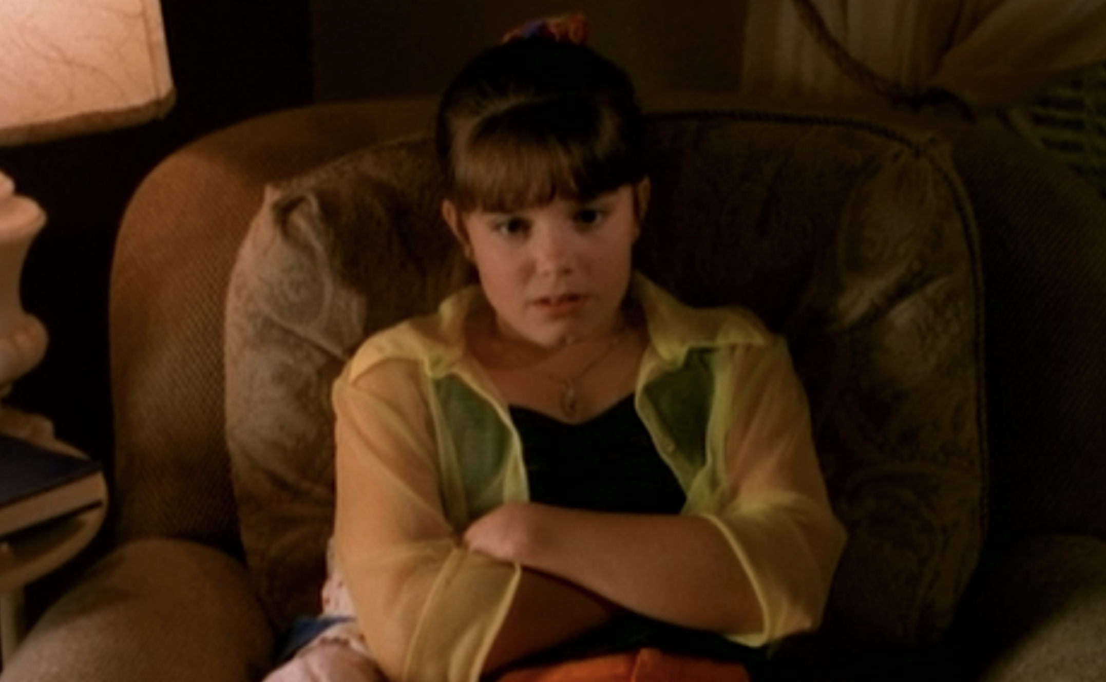 Marnie wearing a bright, see-through button-up over a dark tank top with a scrunchie holding up her hair