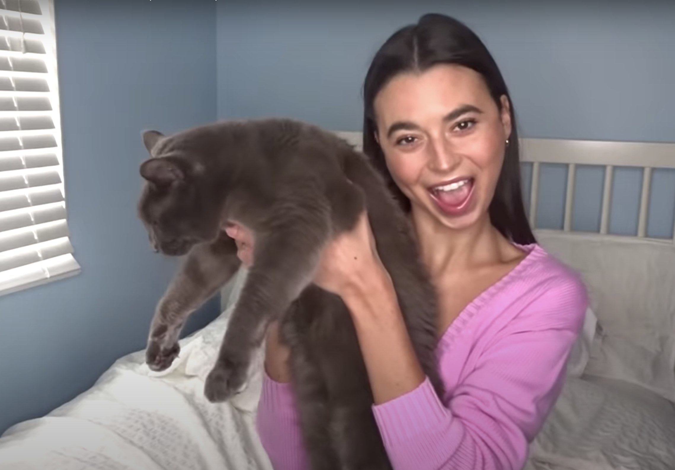 Reina smiles and holds up her grey cat