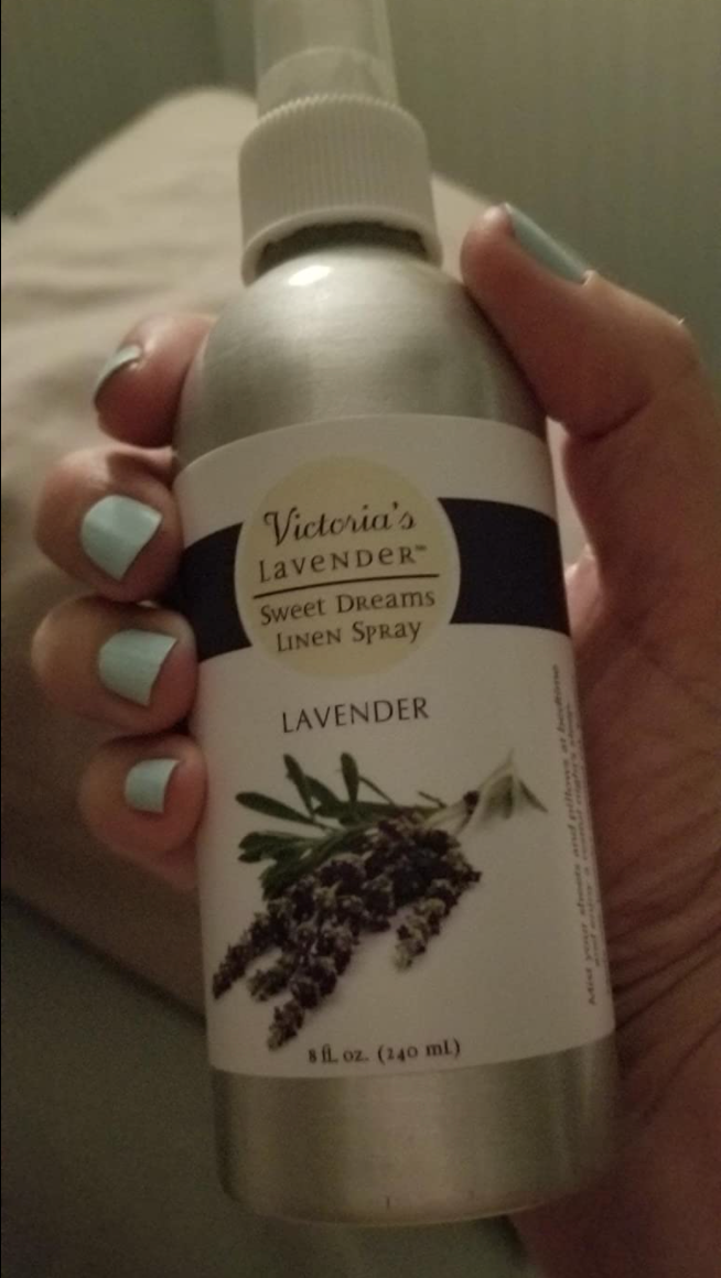 A reviewer holding up a spray bottle of lavender 