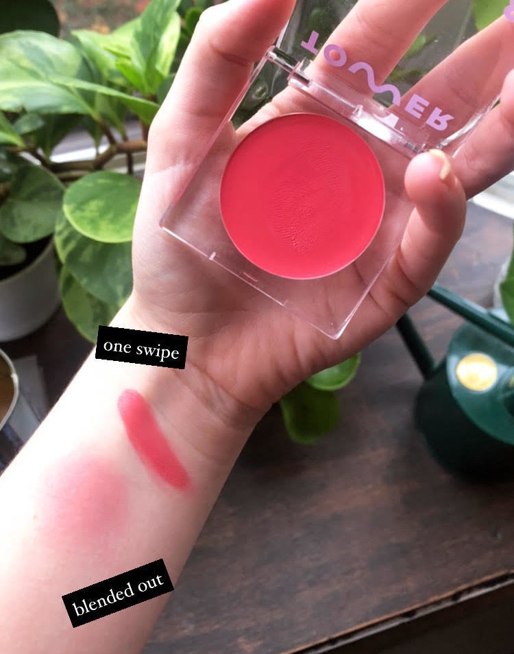 A person holding the blush with two swatches on their arm