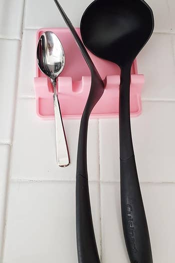 A reviewer's photo of a pink drip pad holding various utensils