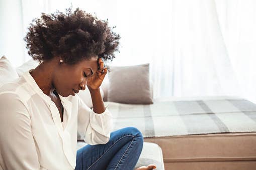 Woman with headache sitting on a couch.