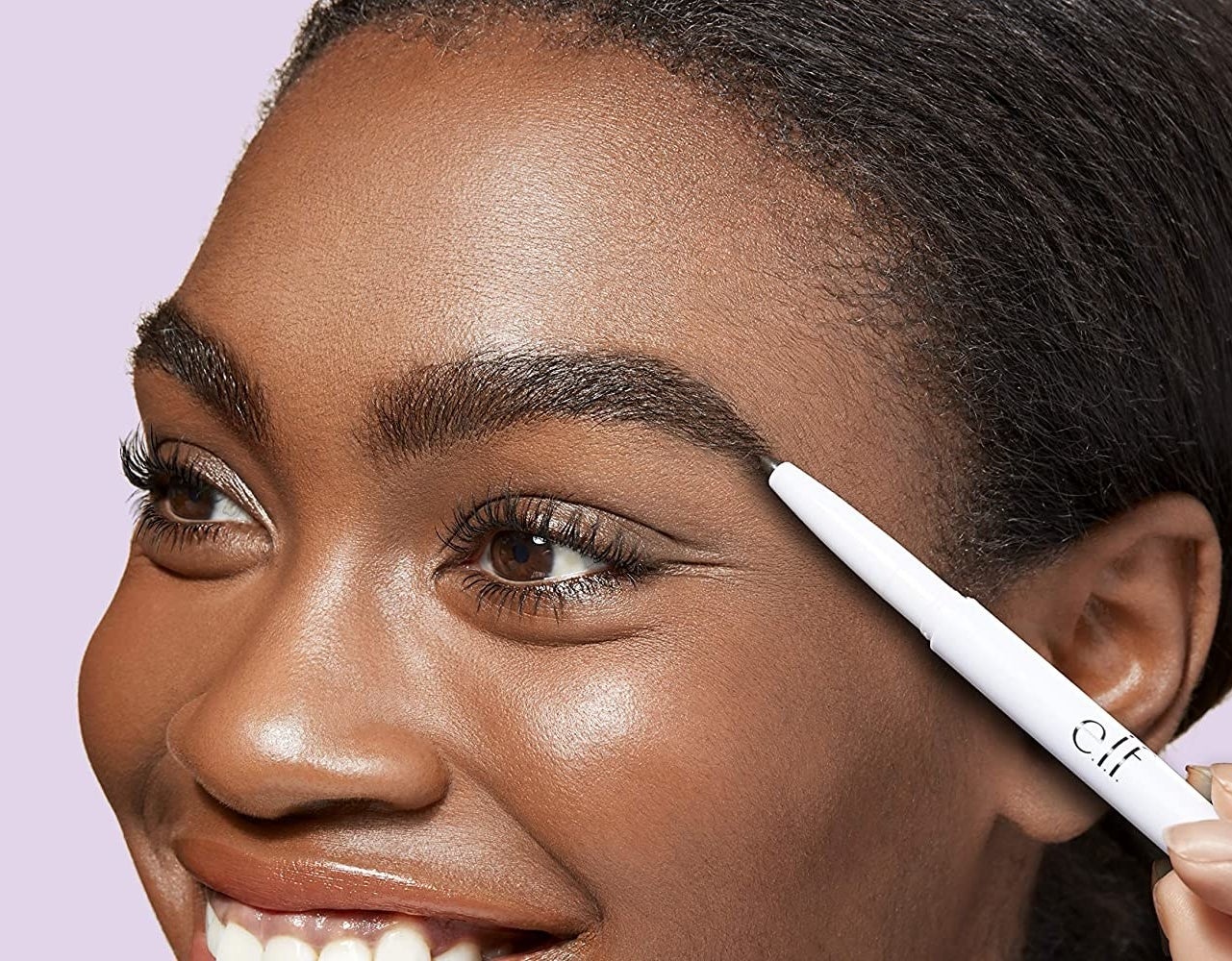 A person using a brow pencils to fill in their brows