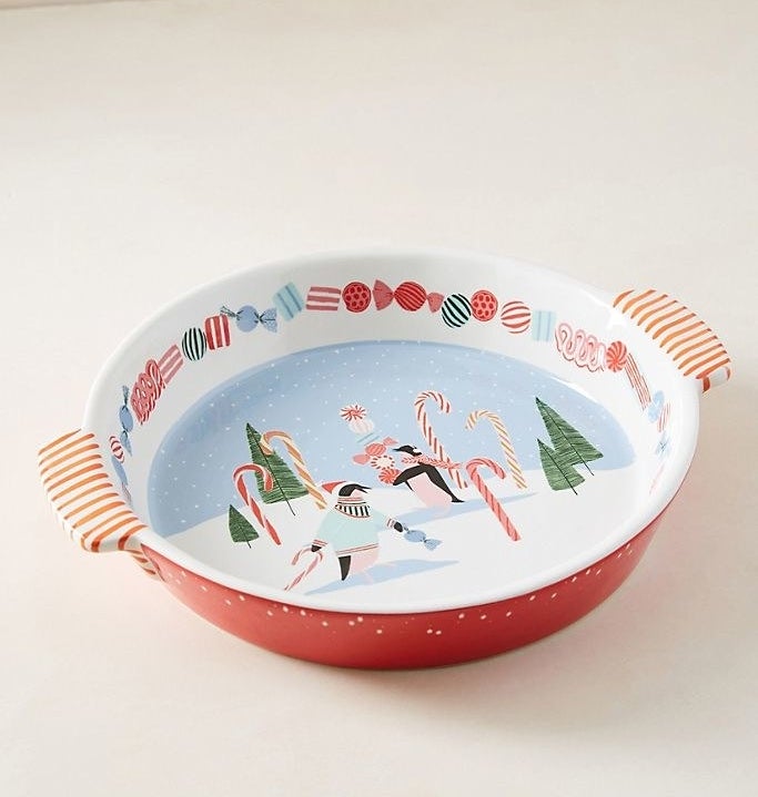 a red pie dish with a white inside showing a wintry scene