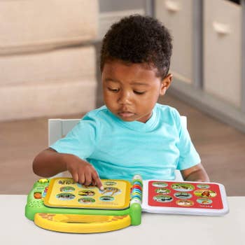 Child pressing button on the LeapFrog 100 Animals book