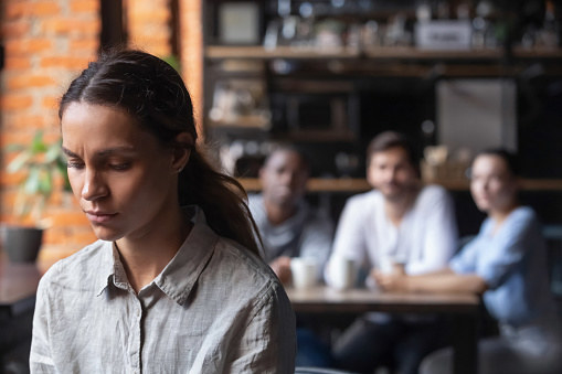 Woman sitting isolated from her friends at a restaurant.