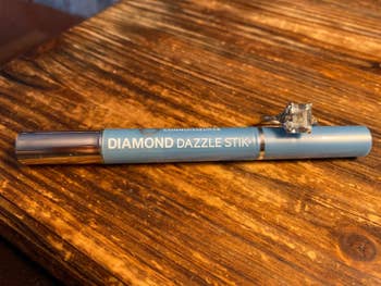 Reviewer pic of the blue stick that's shaped like a pen with a diamond ring resting on it