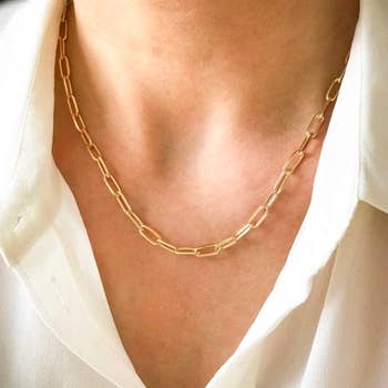 Model wears dainty gold link chain necklace around neck 