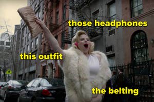 "Smash" character Ivy belting on the street while wearing odd headphones and a Marilyn-Monroe style-outfit