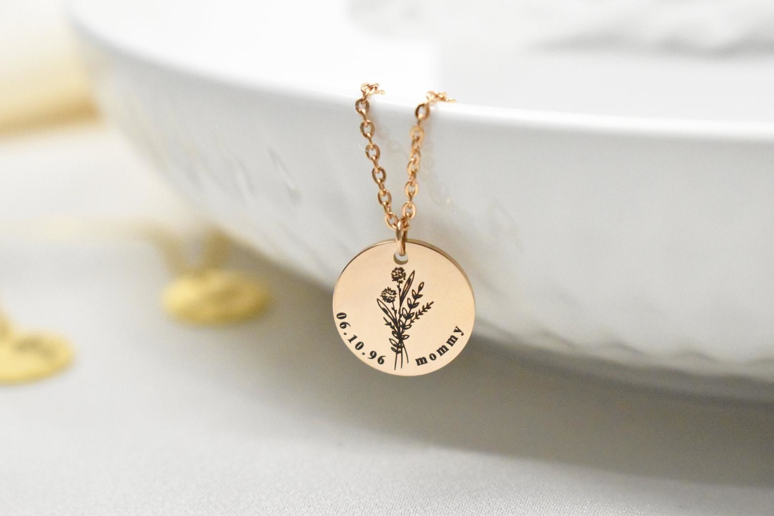 A circular pendant charm in gold with the June birth month flower, a birth date, and the engraving &quot;mommy&quot;