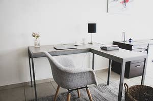 Grey desk and chair with a black lamp and a small vase of flowers