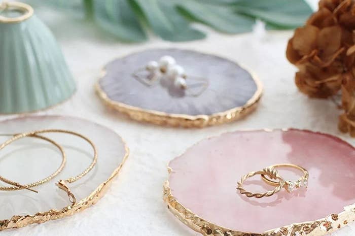 Three gold-dipped coasters with jewelry on them
