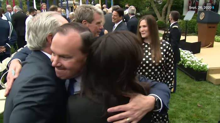 Mike Lee embraces two guests on the Rose Garden lawn