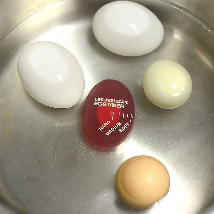 An egg timer in a pot with four eggs.