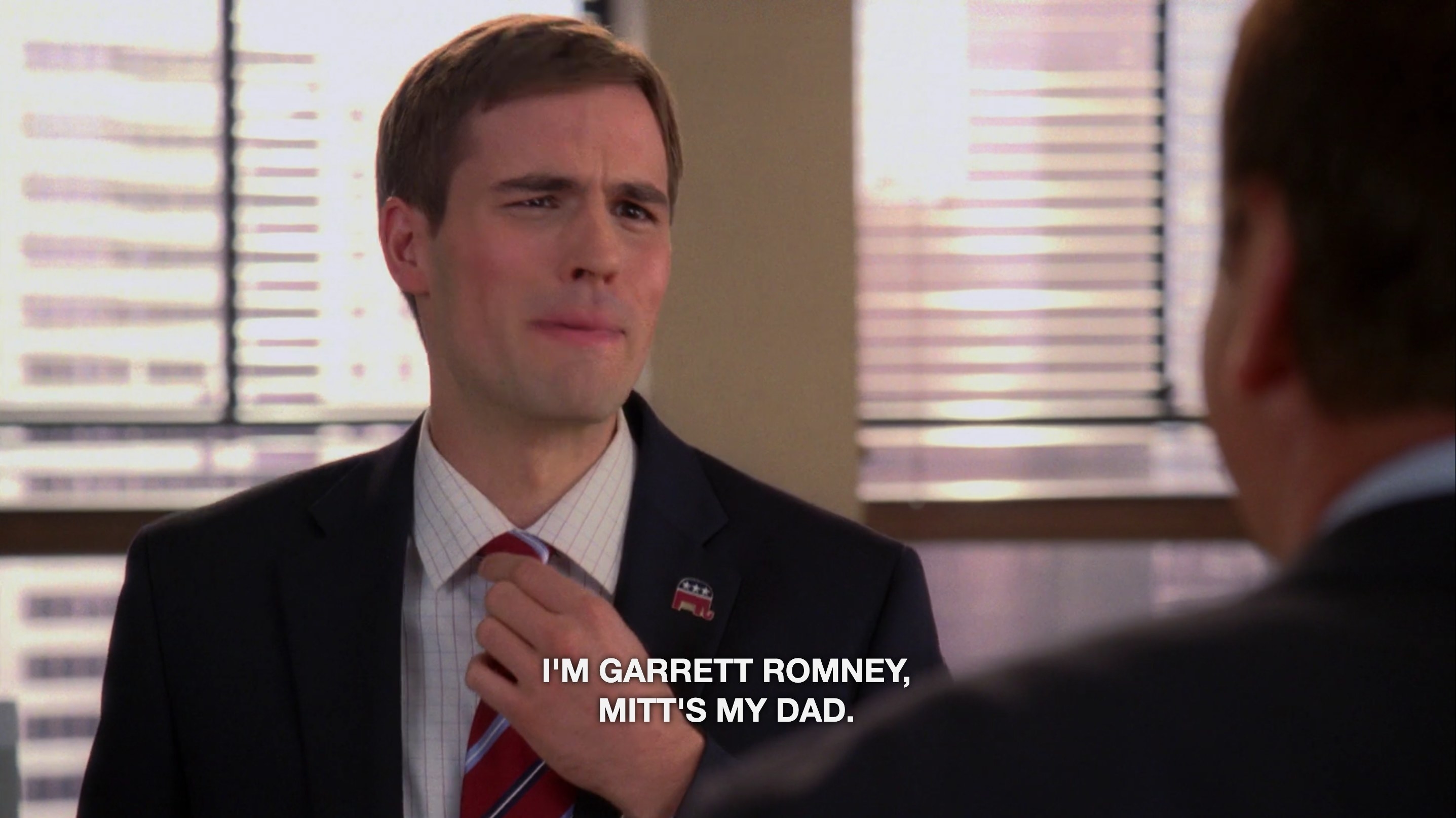 A man in a suit with the caption text &quot;I&#x27;m Garrett Romney, Mitt&#x27;s my dad&quot;