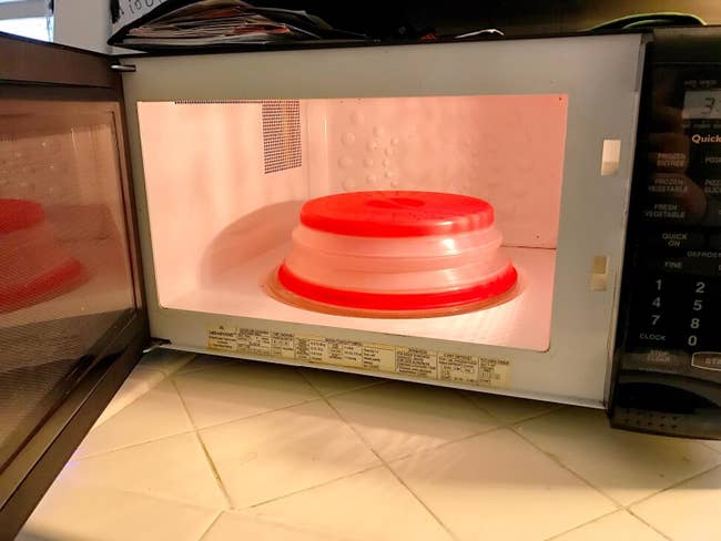 A reviewer's red microwave food cover in their microwave