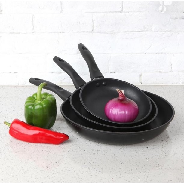 three black mainstay skillets with vegetables around them