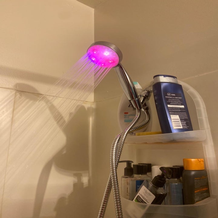 Reviewer photo of the shower head glowing pink in a lit room