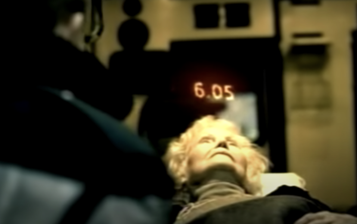 An old women being put on an ambulance with a counter of 6 seconds above her head