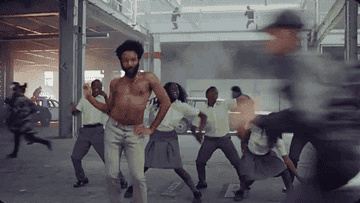 Donald Glover dancing in front of schoolchildren with smoke around