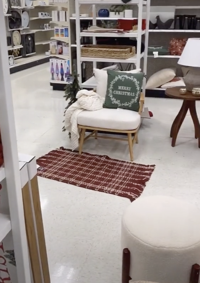 The rearranged chair with pillow that says &#x27;Merry Christmas&#x27;, a blanket in front, and a mini Christmas tree next to it