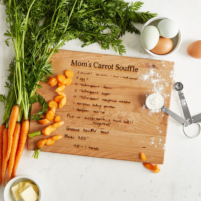 The cutting board, which says &quot;Mom&#x27;s Carrot Souffle&quot; and has the recipe across it