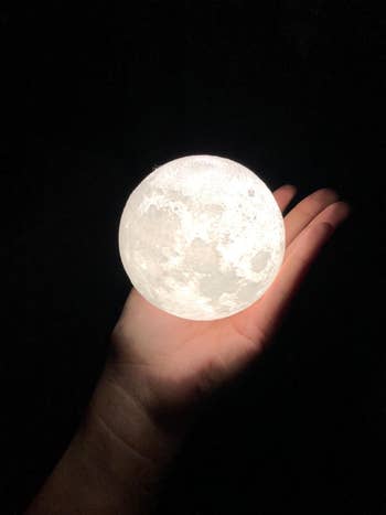 Reviewer holds moon light in hand showing other color / brightness level
