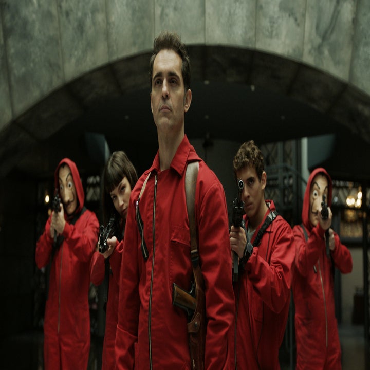 The Money Heist gang from season 1 stands armed and ready in their red jumpsuits