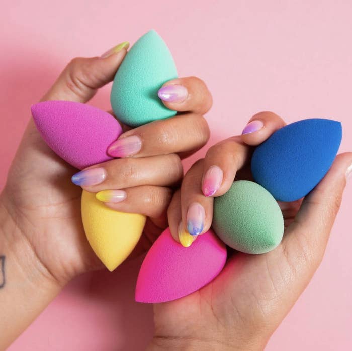 two hands holding six colorful Beautyblenders