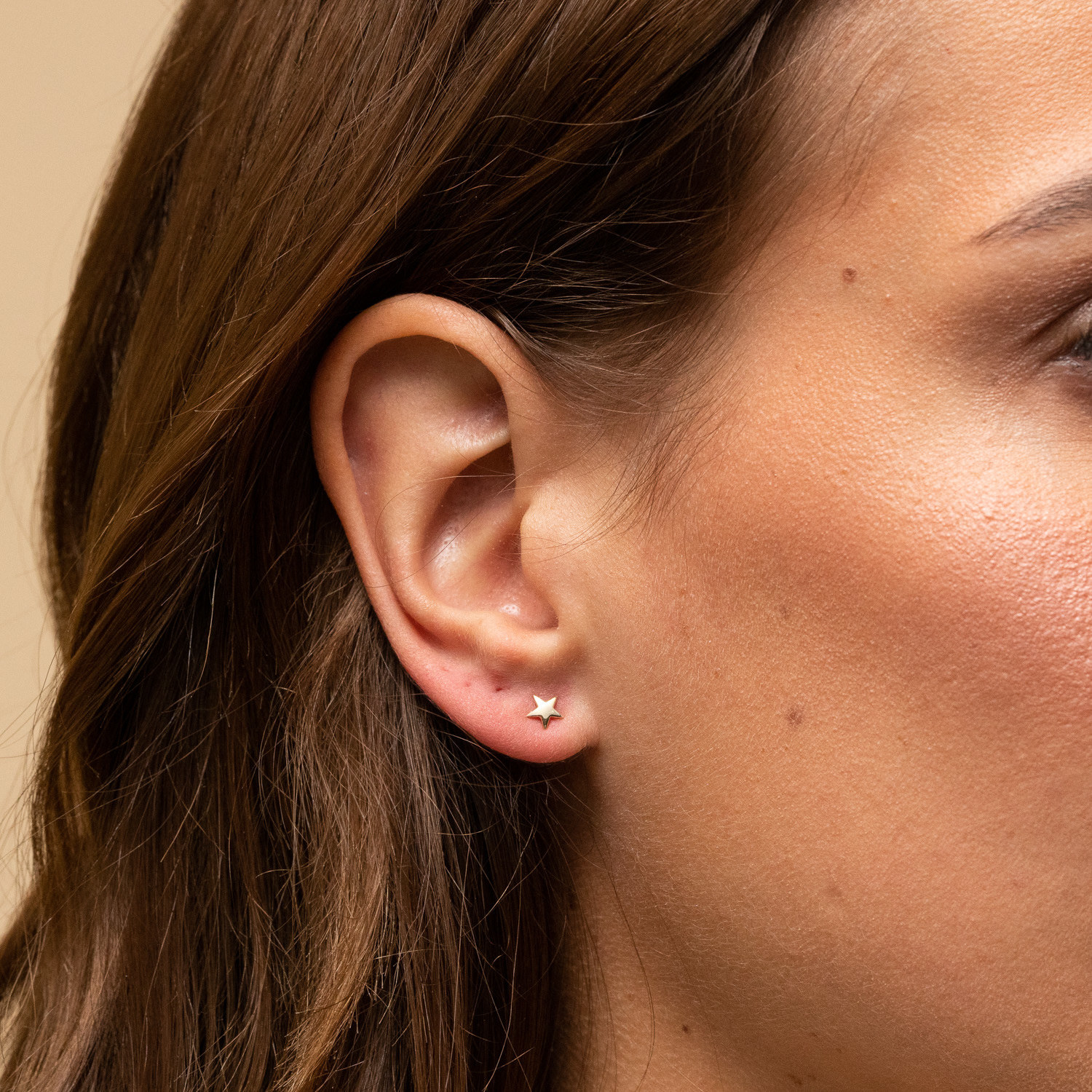 a model wearing tiny gold star stud earrings
