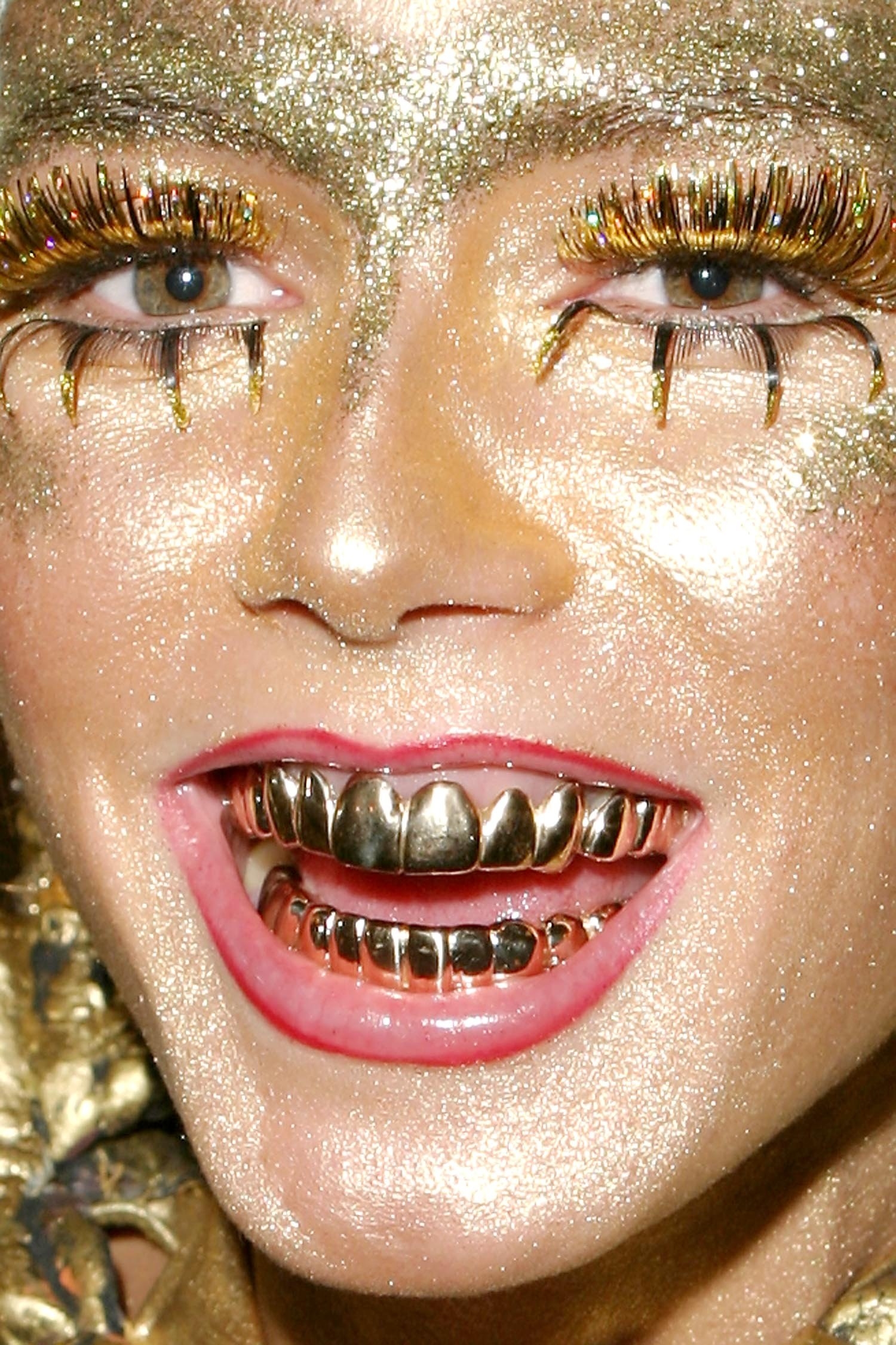 Close up of Heidi Klum&#x27;s face painted gold with grills